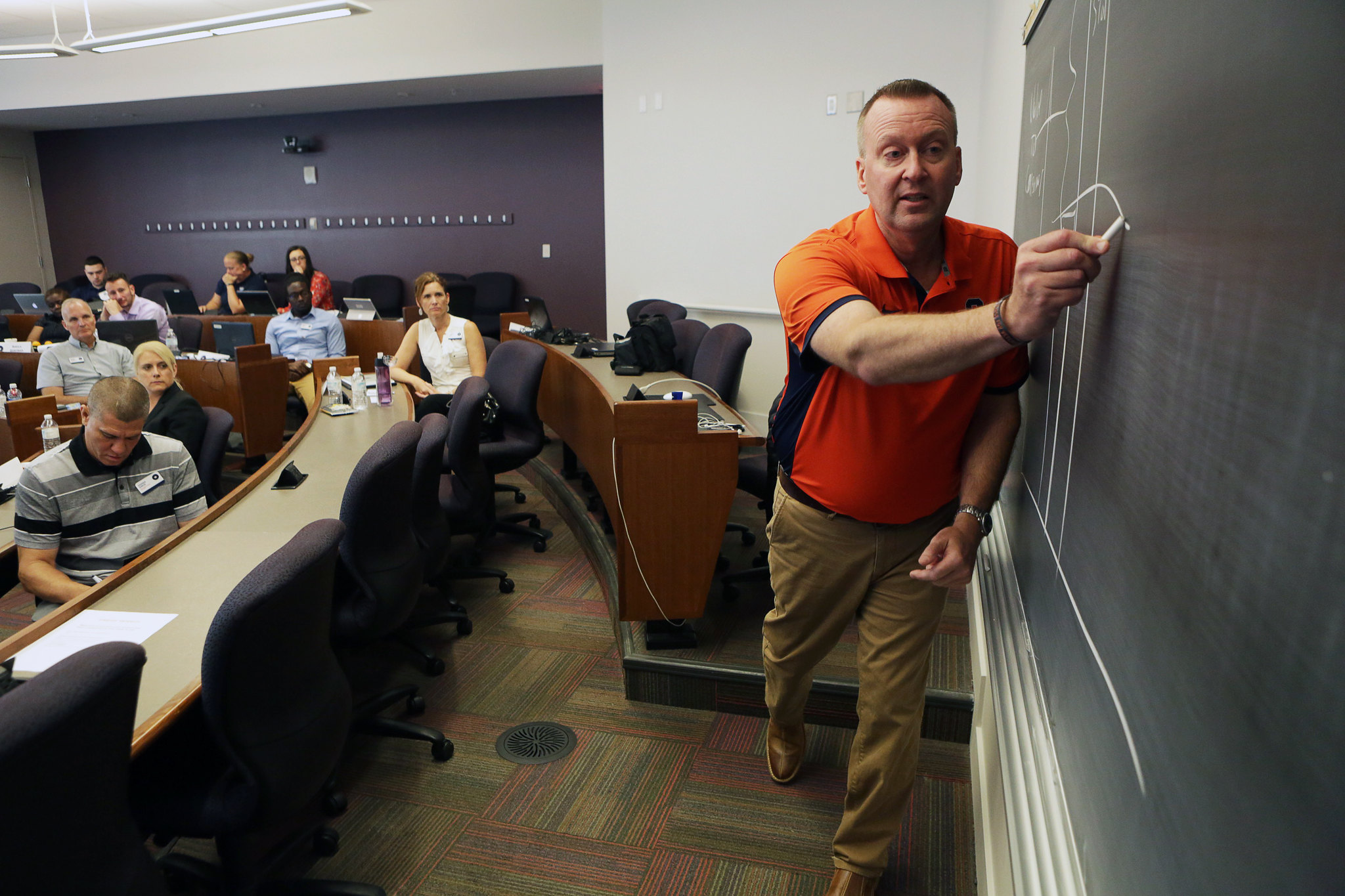Mike Haynie drawing on chalkboard teaching a class.