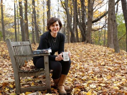 Jill Hinton sitting on bench in woods drinking coffee Jill Hinton sitting on bench in woods drinking coffee